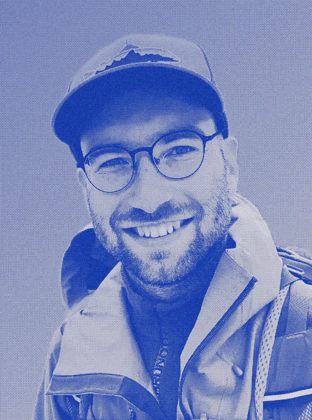 Niklas Jordan, smiling, in a cap and round glasses